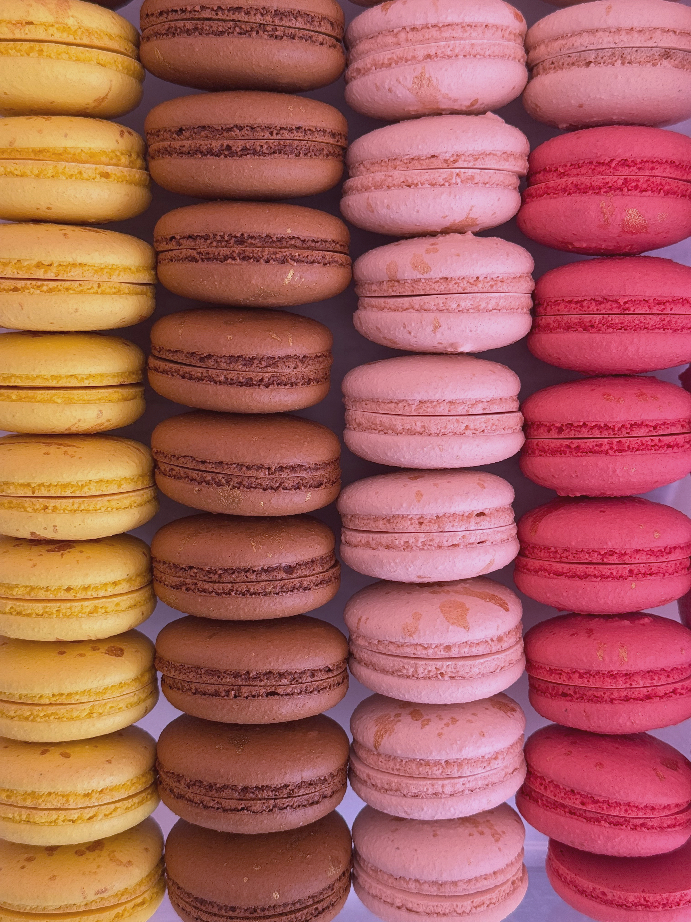 Rows of yellow, chocolate, pink and raspberry macarons stacked side by side