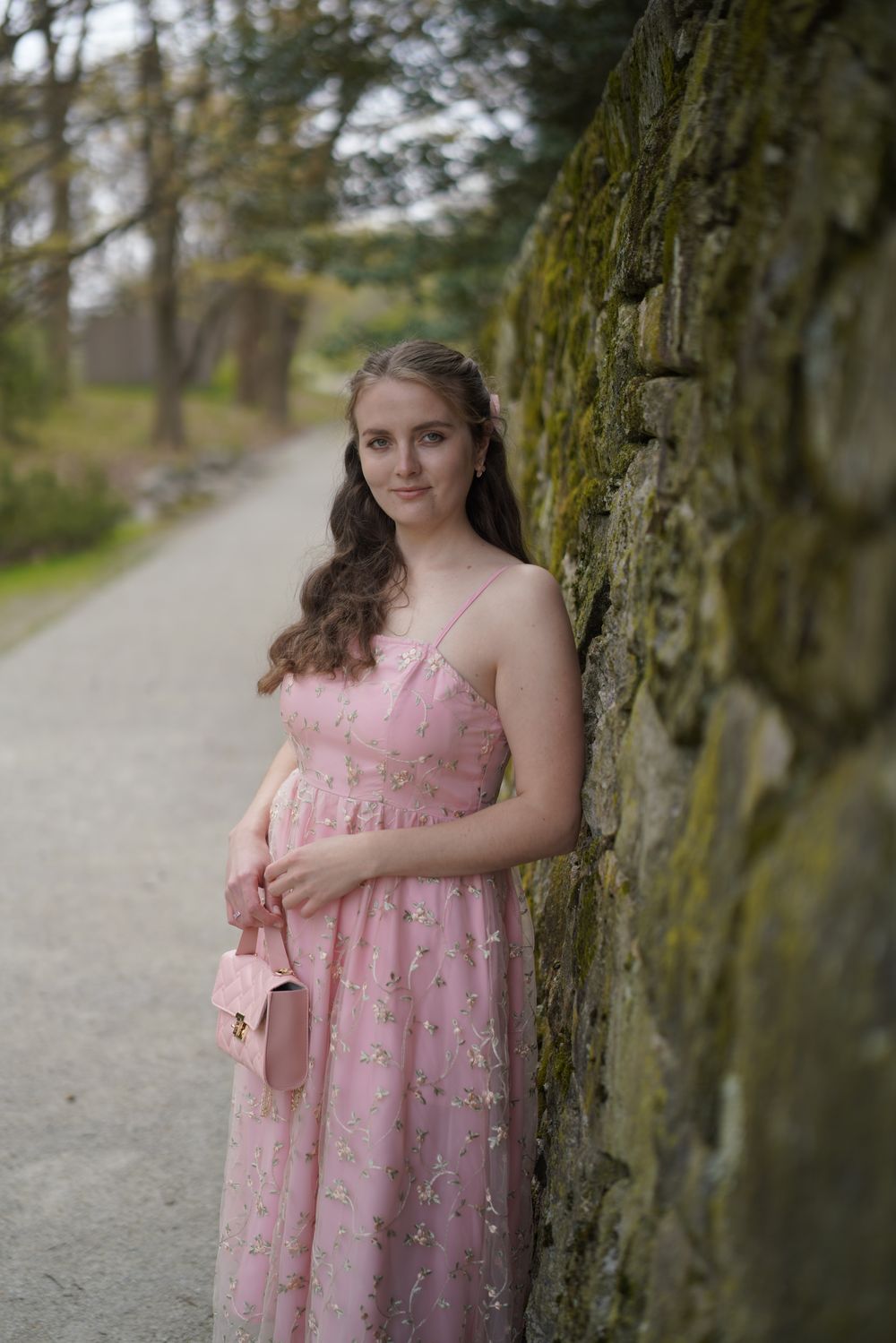 Anastasiia, the baker behind Anastasiia's Bakery, in a pink floral dress beside a stone wall